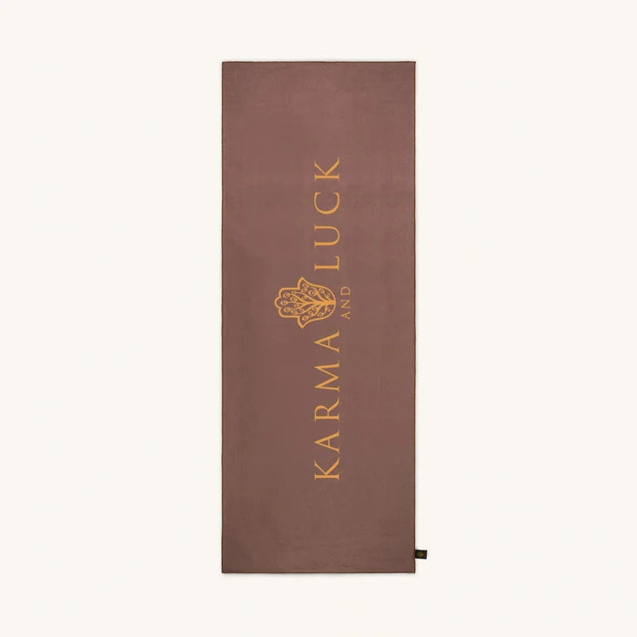Brown yoga towel with 'Karma and Luck' logo on a white background